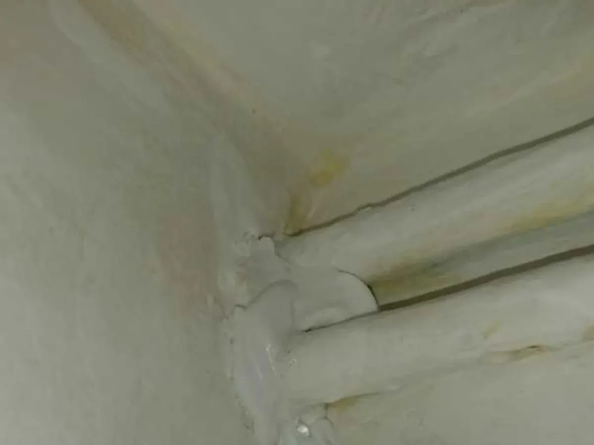 Damp staining around white-painted pipework at the kitchen ceiling