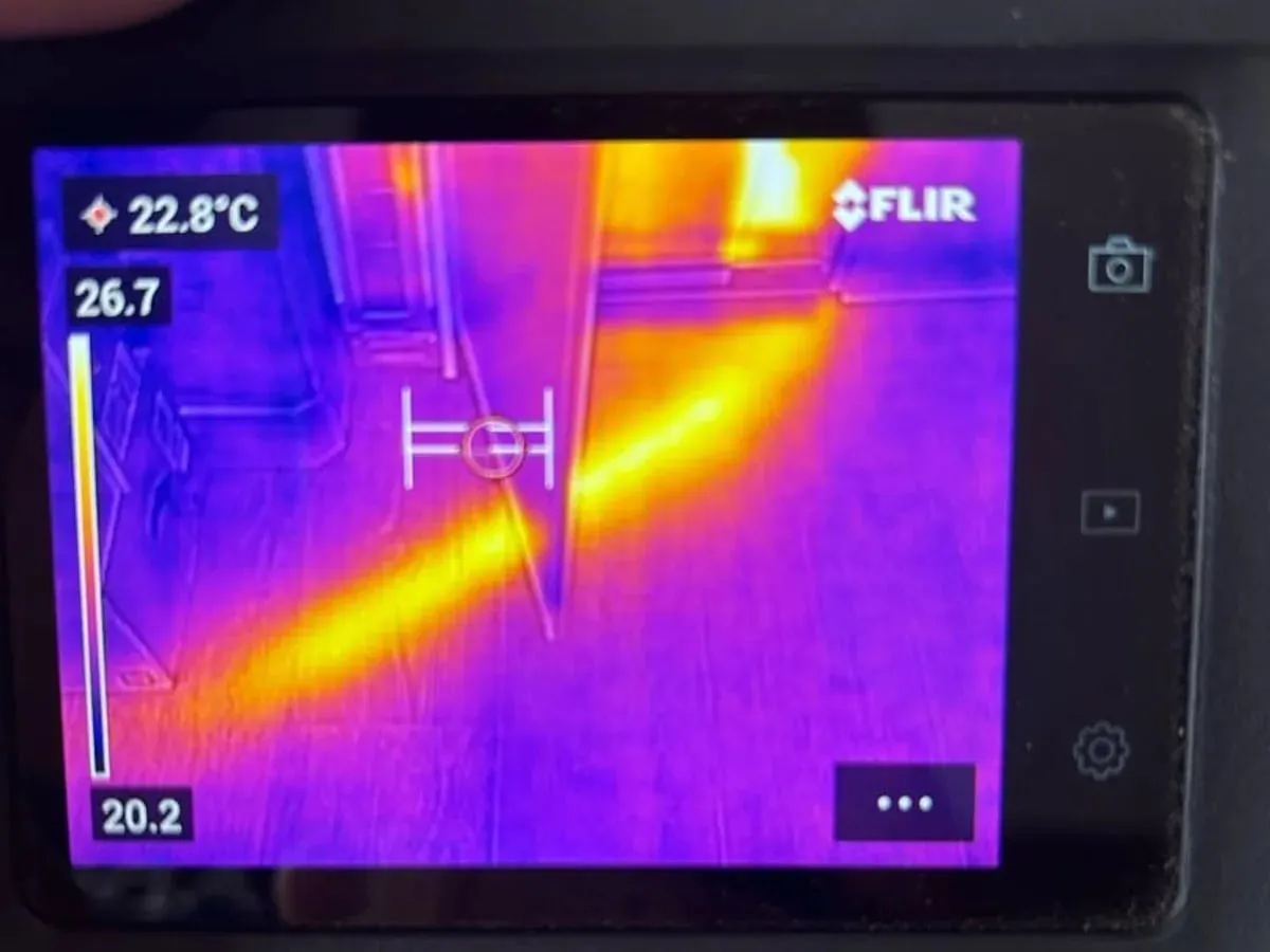 Thermal camera display showing warm pipe routes beneath a kitchen floor